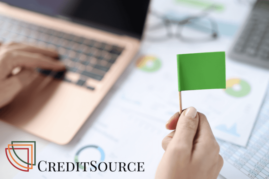 Person at desk holds a small green flag representing a financial signal assessed favourably by tender evaluators.