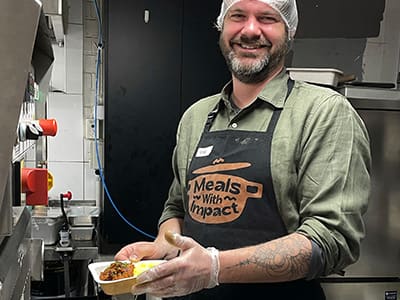 BidWrite employee Robin volunteering in the kitchen at Meals for Impact as part of a community impact initiative.